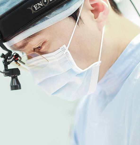 수술모·마스크·확대경을 쓴 의사 옆모습