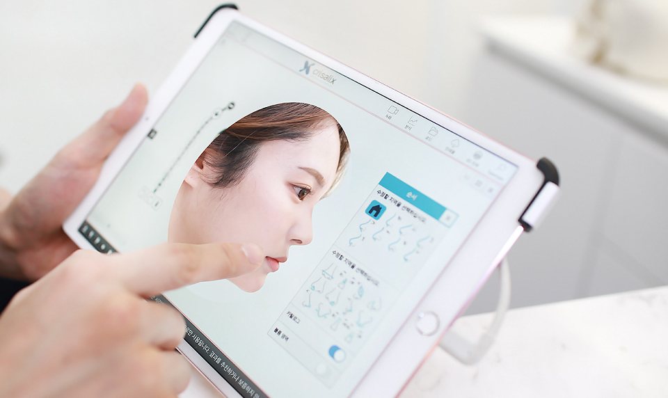 크리살릭스 3D 가상성형 화면이 뜬 태블릿을 손가락으로 가리킴