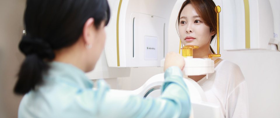 3D CT 촬영을 돕는 직원과 장비 속 여성