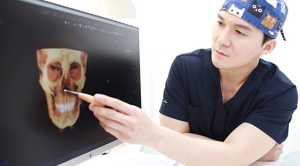원장이 모니터의 3D 두개골 CT 영상을 펜으로 가리킴