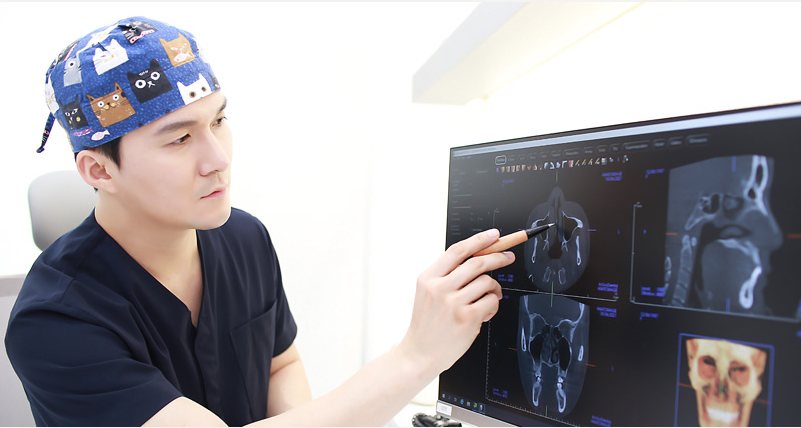 수술모 쓴 원장이 CT 화면을 펜으로 가리키며 분석하는 장면