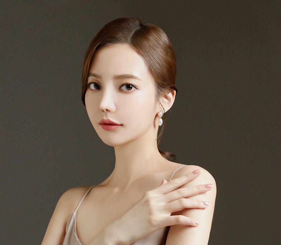 어깨에 손을 얹은 긴 머리 모델(짙은 갈색 배경)